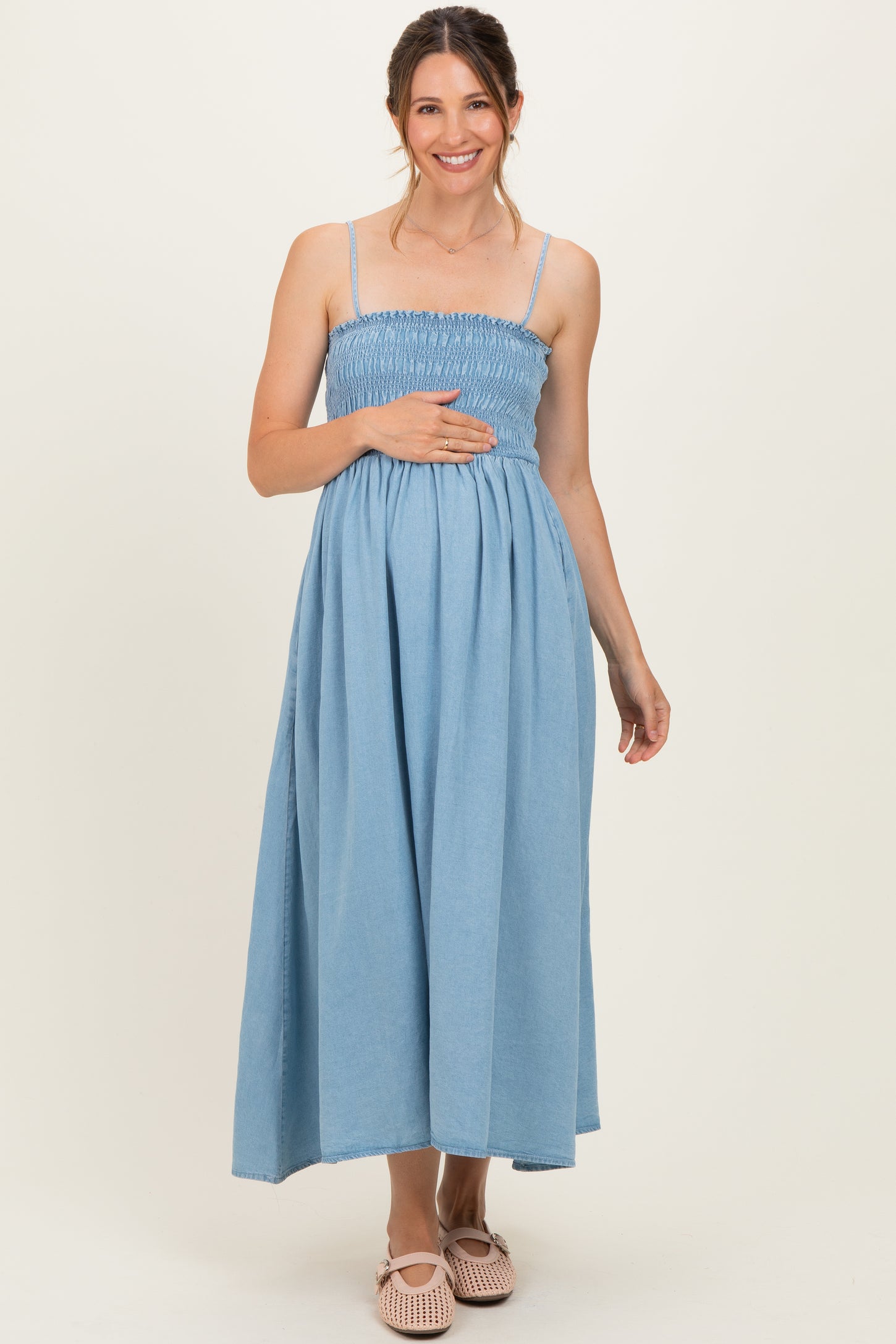 woman wearing a light blue maternity dress with smocked bodice and a visible baby bump