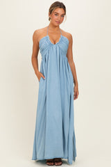woman wearing a light blue halter neck maxi dress with a gathered bodice and side pockets