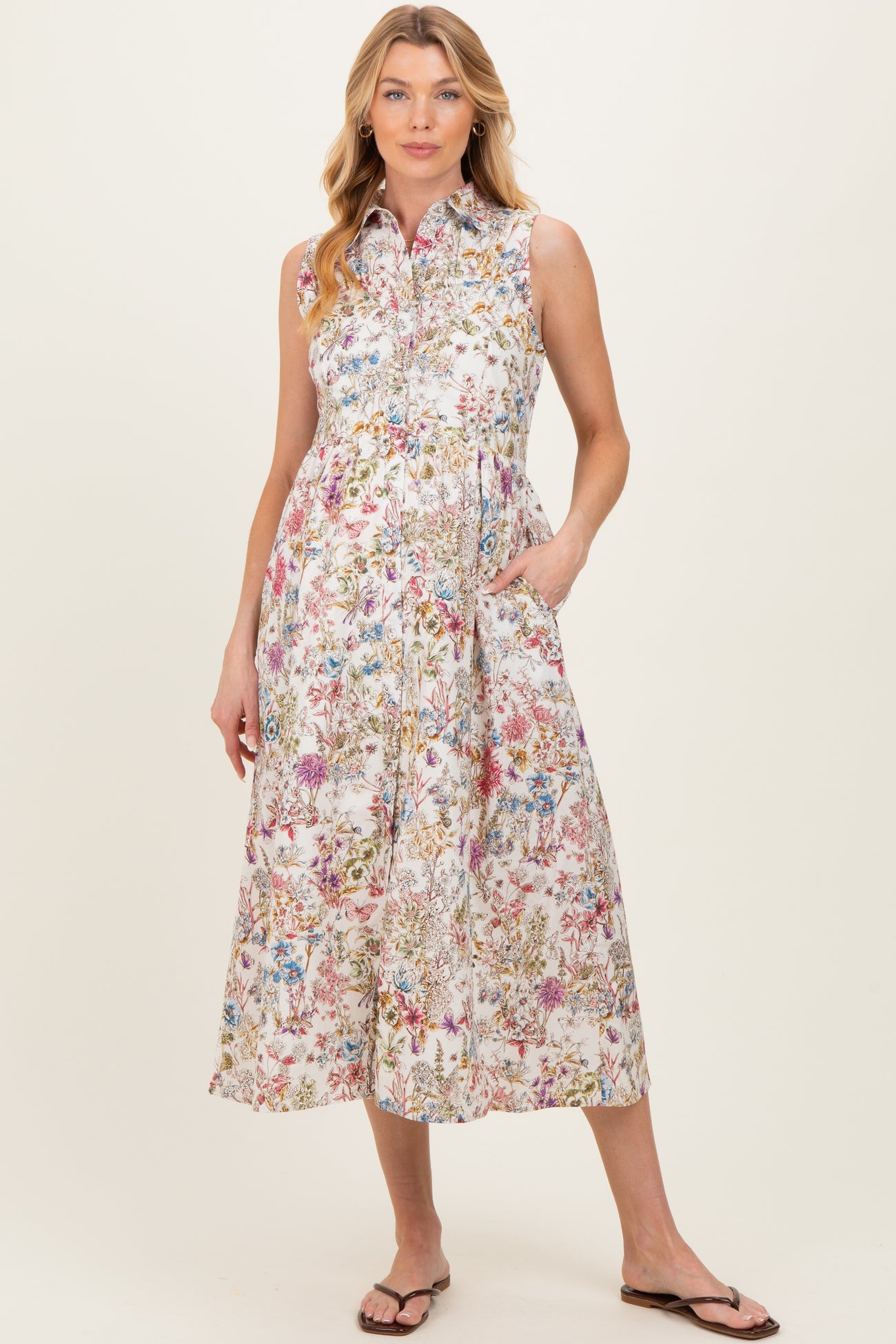 woman wearing a floral print sleeveless maternity dress with pockets and a collared neckline