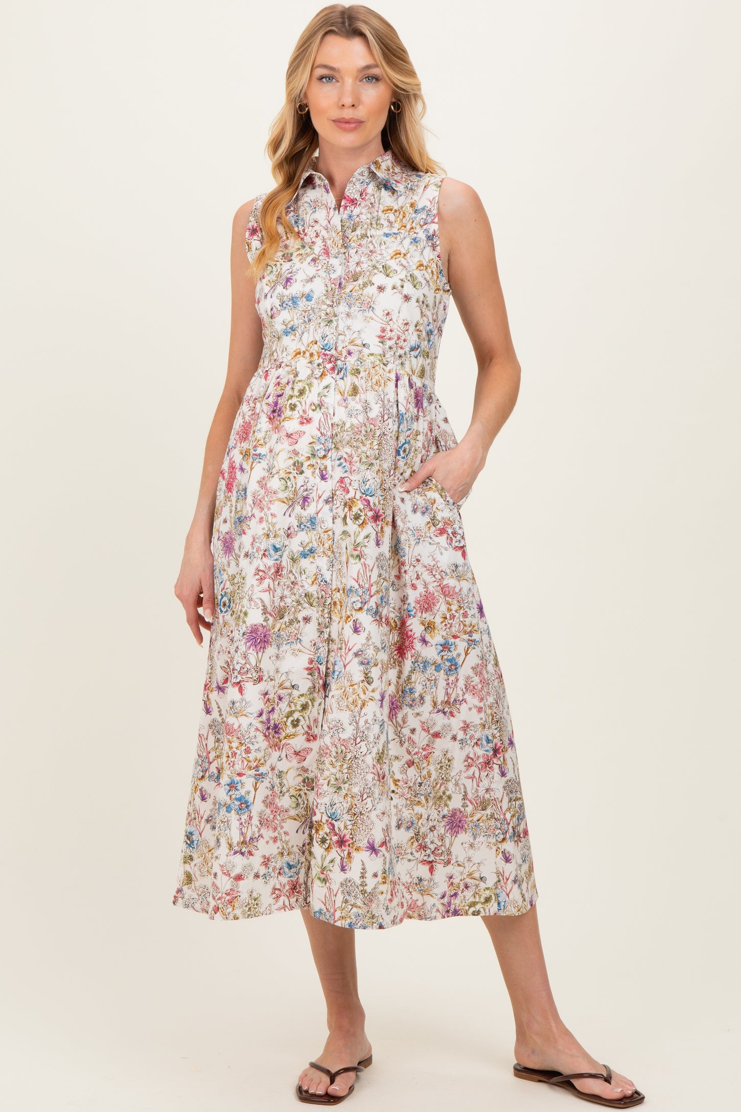 woman wearing a floral print sleeveless maternity dress with pockets and a collared neckline
