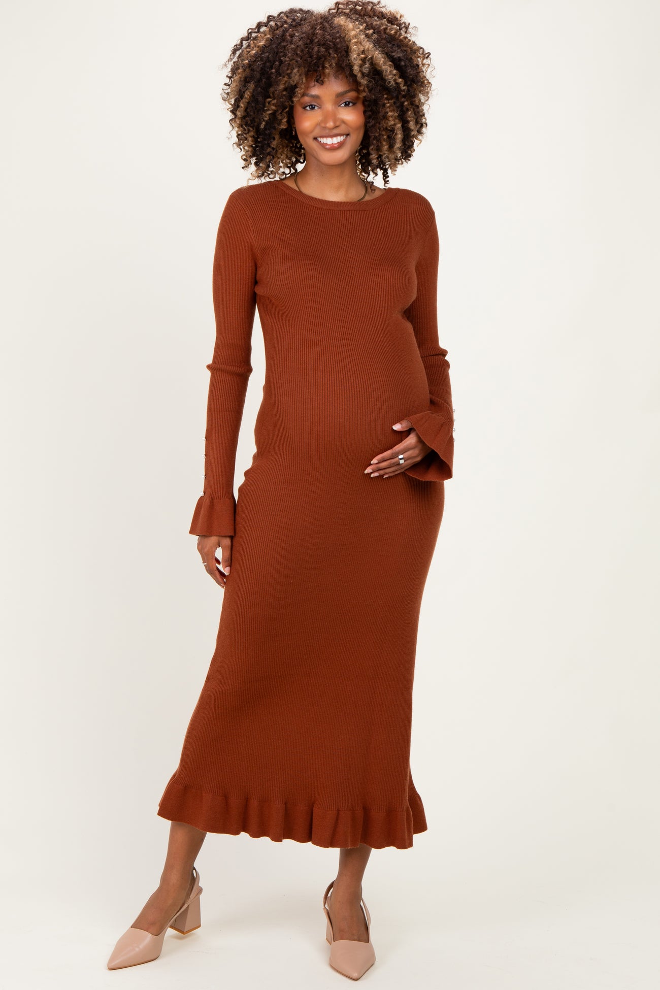 woman wearing a rust ribbed maternity dress with ruffled hem and bell sleeves, showing her baby bump