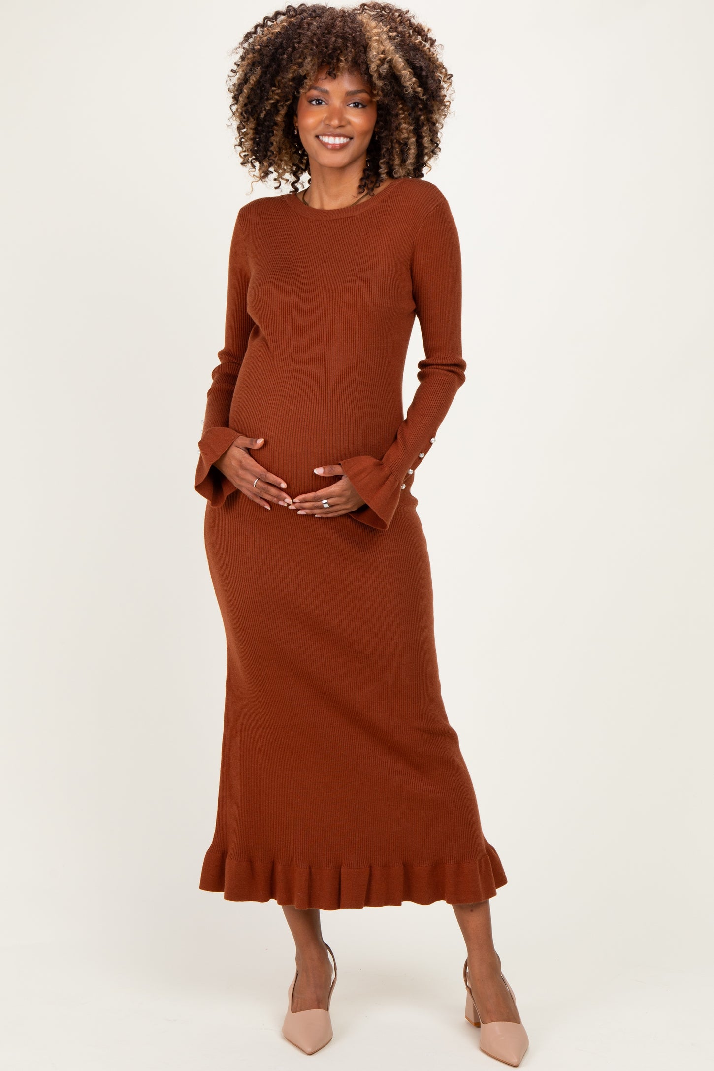 woman wearing a rust long sleeve ribbed maternity dress with ruffle hem and baby bump visible