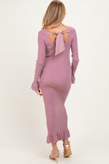 woman wearing a dusty pink long sleeve maternity dress with back cutout and ribbon tie, featuring ruffle hem detail