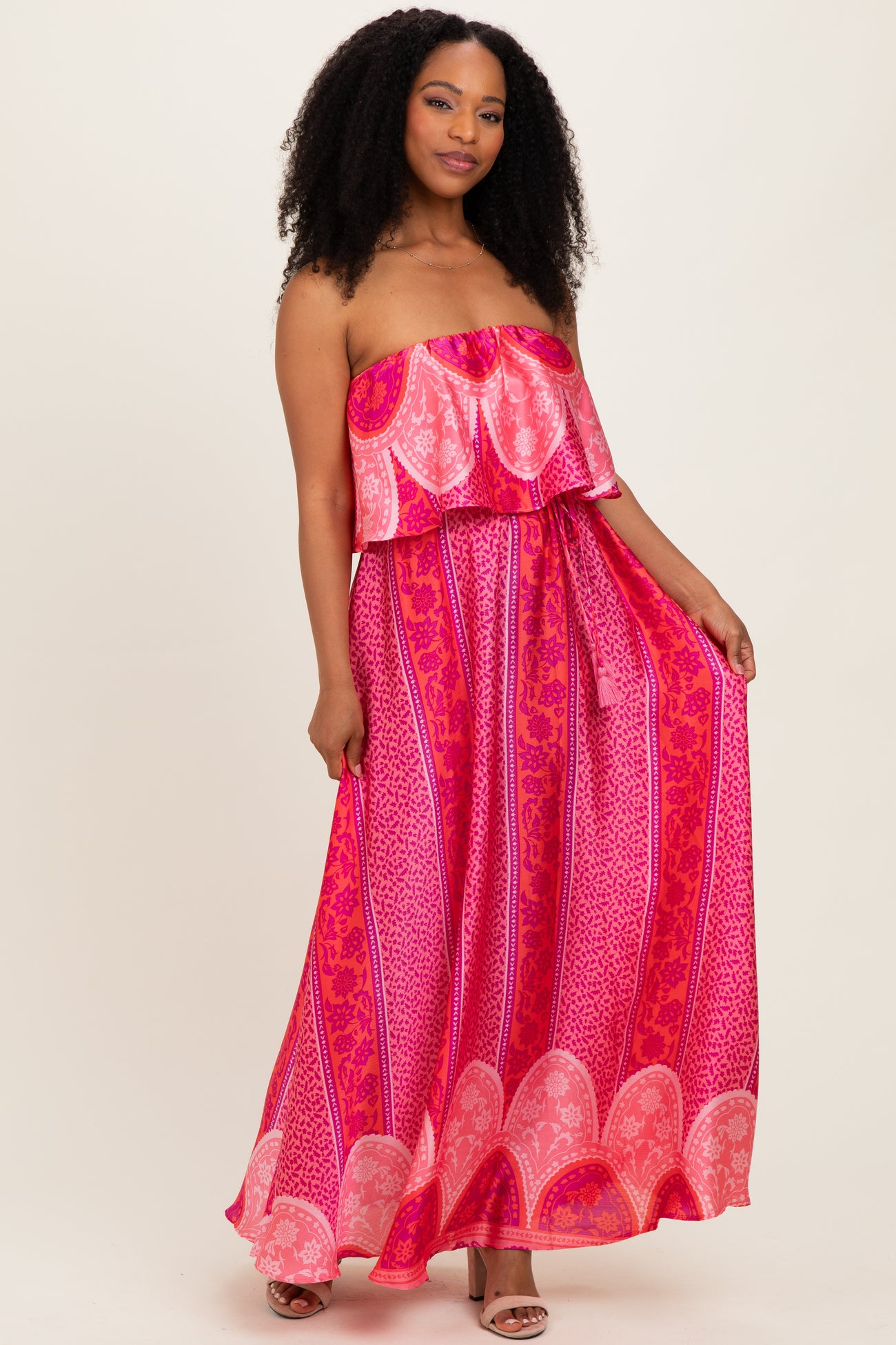 woman wearing a pink strapless maxi dress with a ruffled top and a patterned skirt
