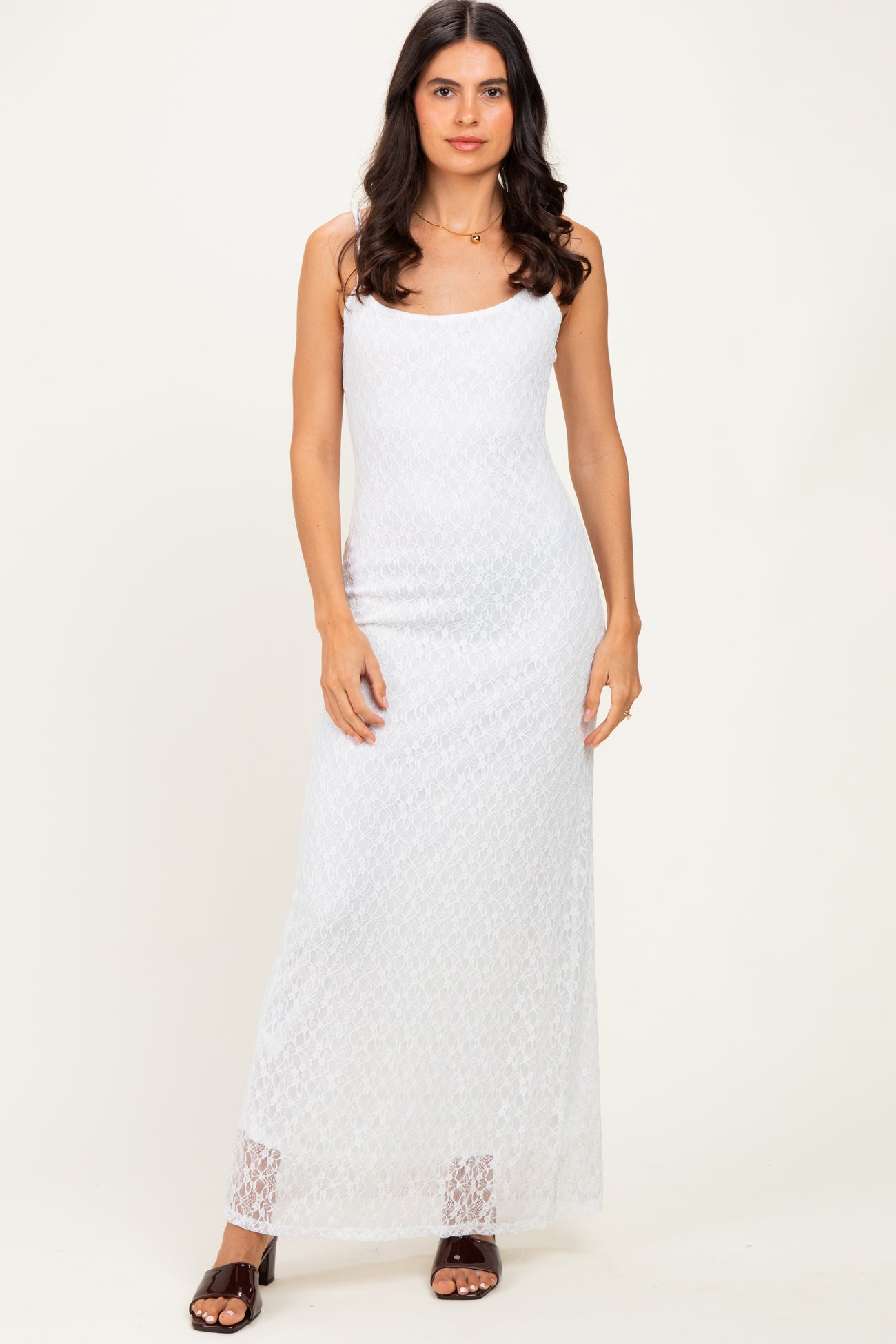 woman wearing a white lace maxi dress with adjustable straps and a fitted silhouette