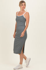 woman wearing a dark green ribbed midi dress with white straps and side slit, paired with white sneakers