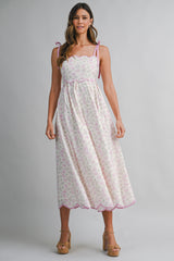 woman wearing a floral print midi dress with pink scalloped edges and tie straps