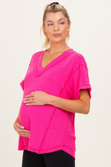 woman wearing a bright pink v-neck maternity top and holding her baby bump
