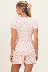 woman wearing a light pink floral maternity pajama set with a short sleeve top and shorts, showing a comfortable fit