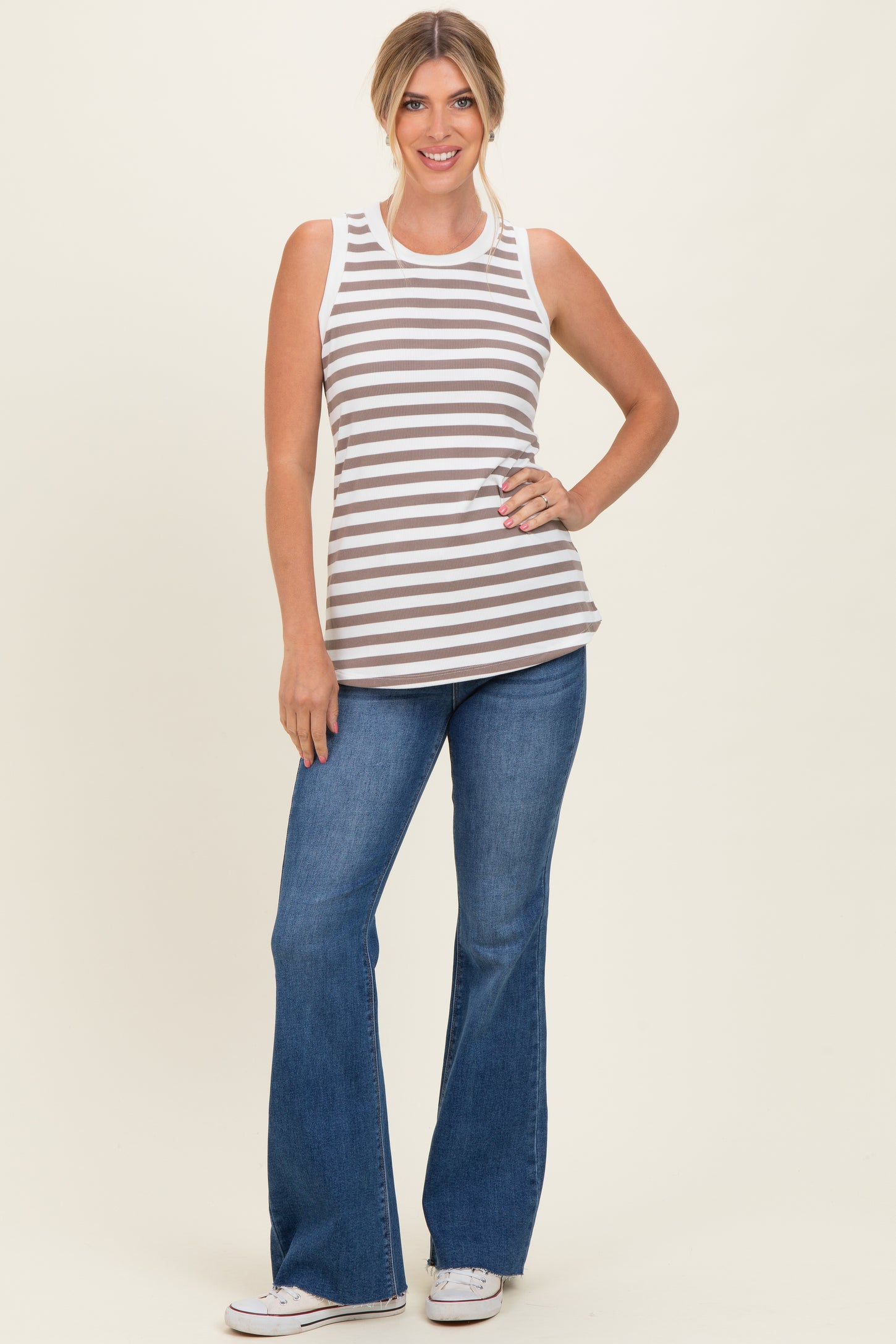 woman wearing a brown and white striped sleeveless top with blue flared jeans