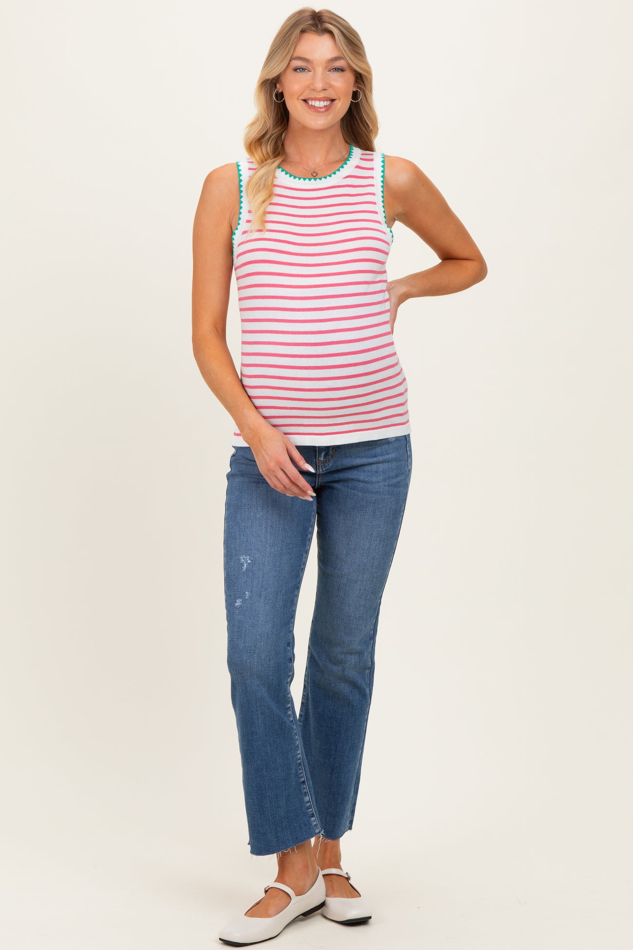 woman wearing a striped maternity tank top with colorful detailing and paired with blue jeans