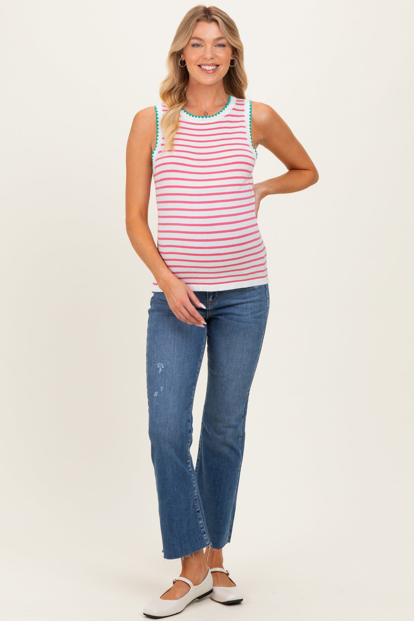 woman wearing a striped maternity tank top with colorful detailing and paired with blue jeans