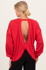 woman wearing a red maternity top with an open back and long sleeves, showcasing a relaxed fit and comfortable style