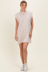 woman wearing a beige short sleeve dress with a relaxed fit and white sneakers