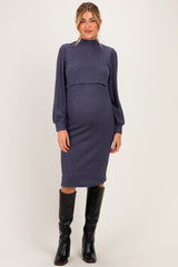 woman wearing a dark blue maternity sweater dress with long puff sleeves and a fitted skirt, showcasing her baby bump