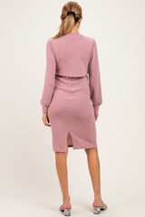 woman wearing a pink ribbed maternity dress with long sleeves and a back slit detail