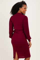 woman wearing a burgundy ribbed dress with a back cutout and long sleeves, showing a side slit at the bottom