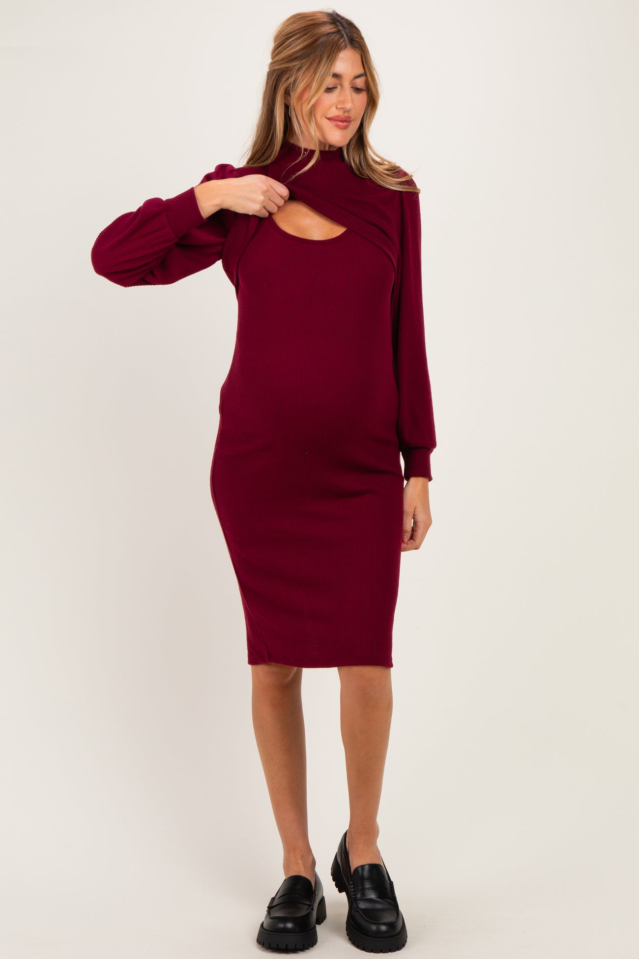 woman wearing a burgundy ribbed maternity dress with a cut-out detail and long sleeves, showcasing her baby bump