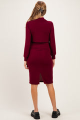 woman wearing a burgundy ribbed maternity dress with a back slit and long sleeves