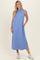 woman wearing a sleeveless light blue maxi dress with side pockets and side slits, styled with white sneakers