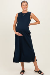woman wearing a navy blue sleeveless maternity dress with side slits and holding her baby bump
