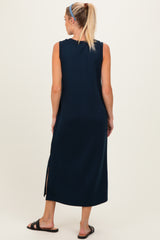 woman wearing a navy blue sleeveless maternity maxi dress with side slits, standing with her back to the camera