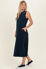 woman wearing a navy blue sleeveless maxi dress with side pockets and black sneakers