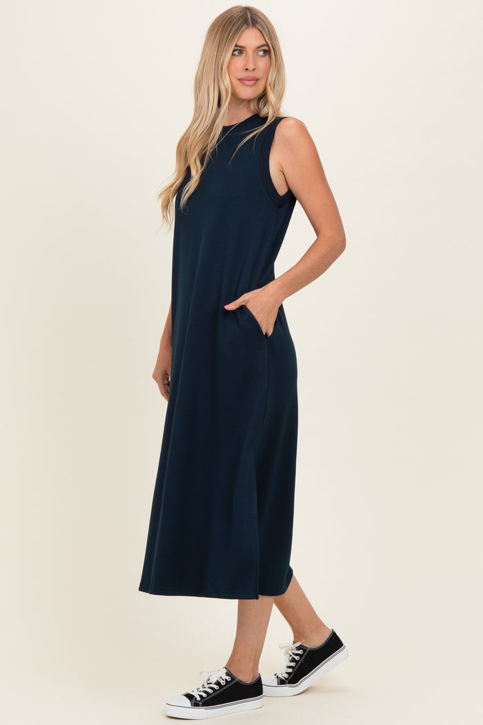 woman wearing a navy blue sleeveless maxi dress with side pockets and black sneakers