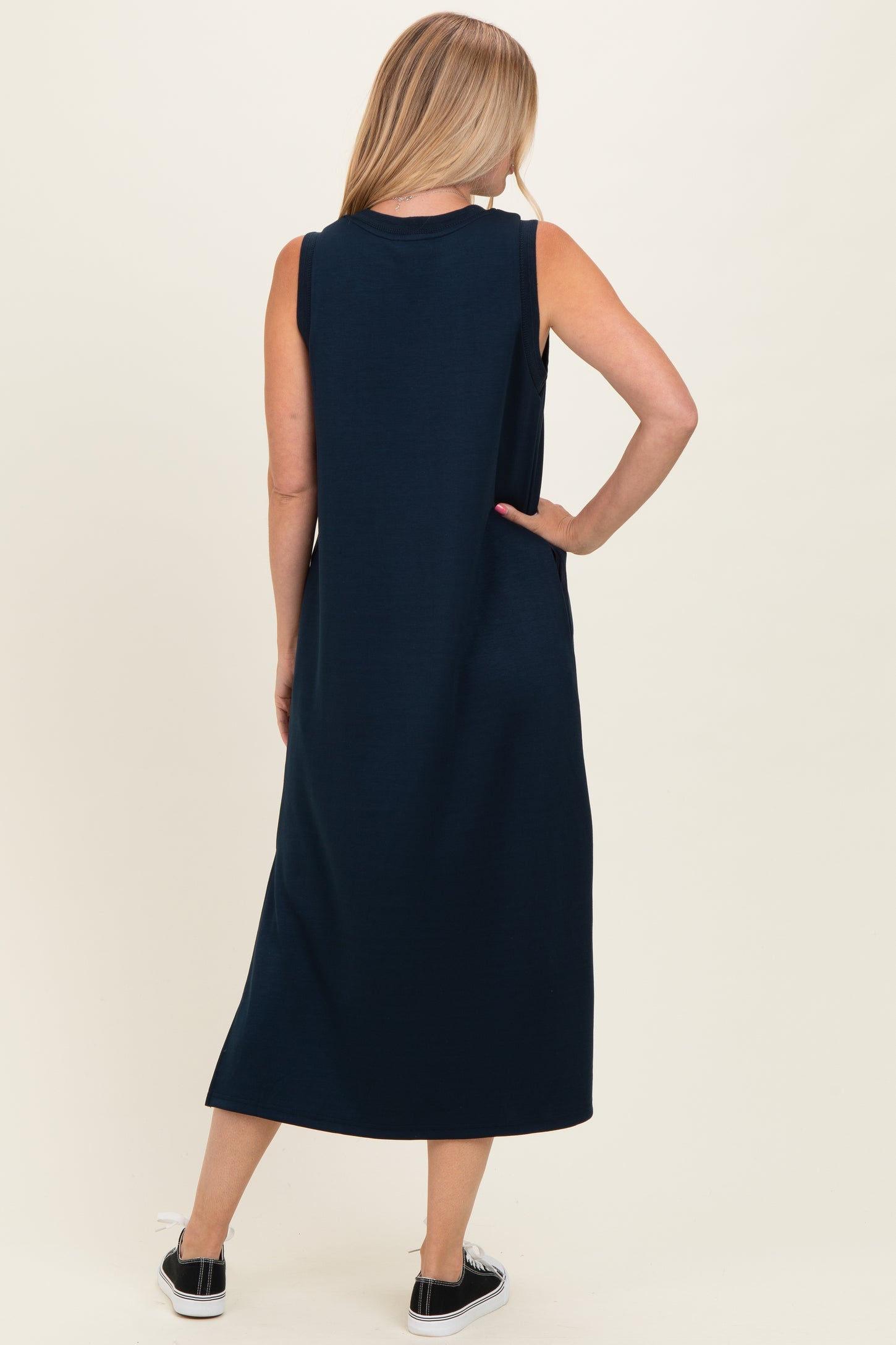 woman wearing a navy blue sleeveless maxi dress, seen from the back with a relaxed fit and a long silhouette