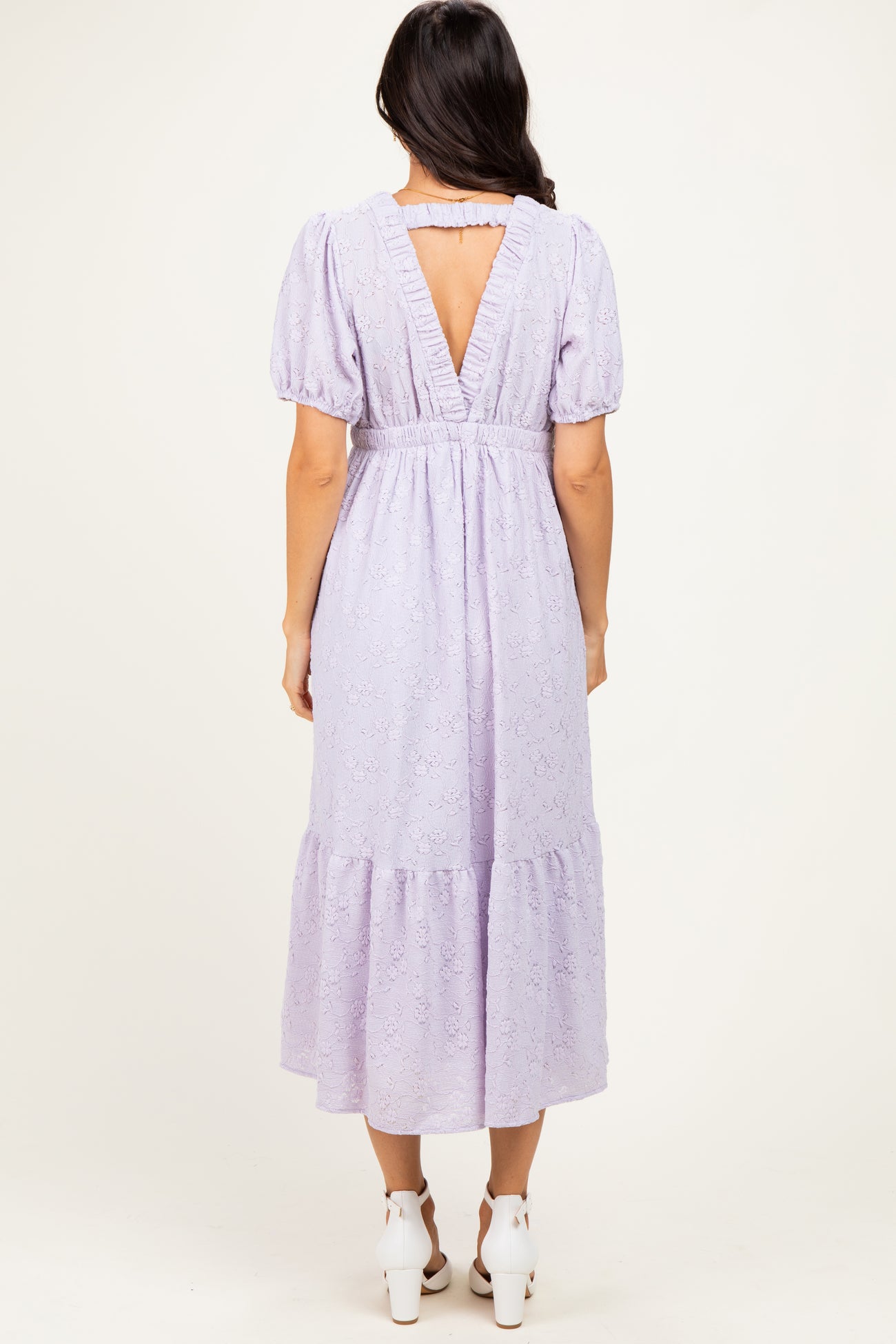 woman wearing a lavender puff sleeve midi dress with a tiered hem and a v-back detail
