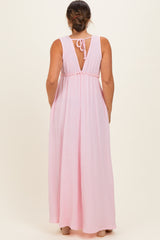 woman wearing a pink backless maternity maxi dress with a tie detail and a flowing fit
