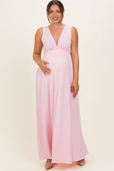 woman wearing a pink sleeveless maternity maxi dress with a deep v-neck and a baby bump