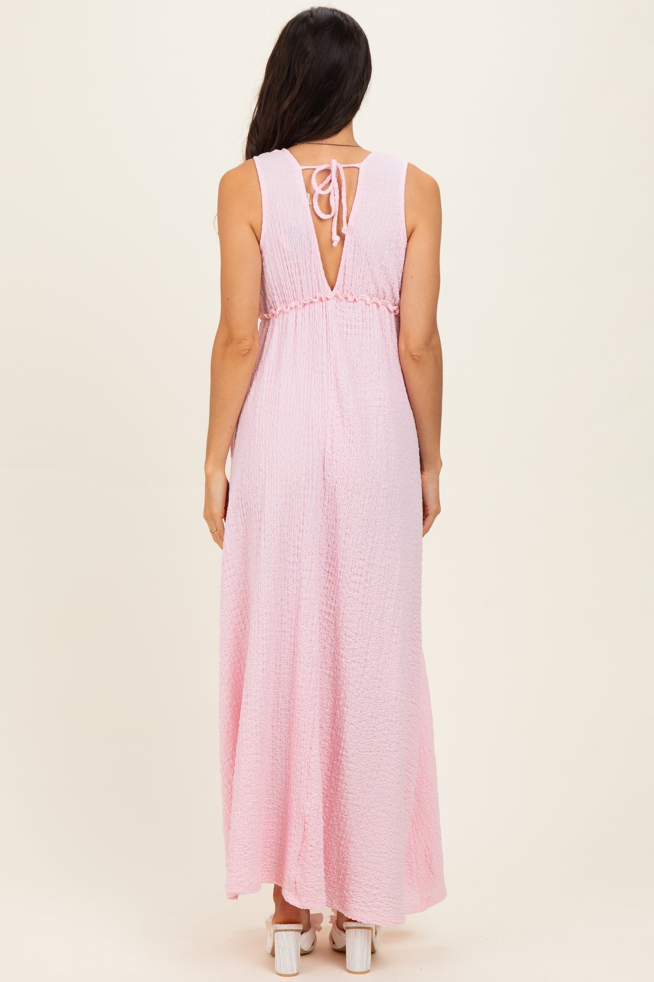 woman wearing a pink sleeveless maxi dress with a back tie and a flowy skirt