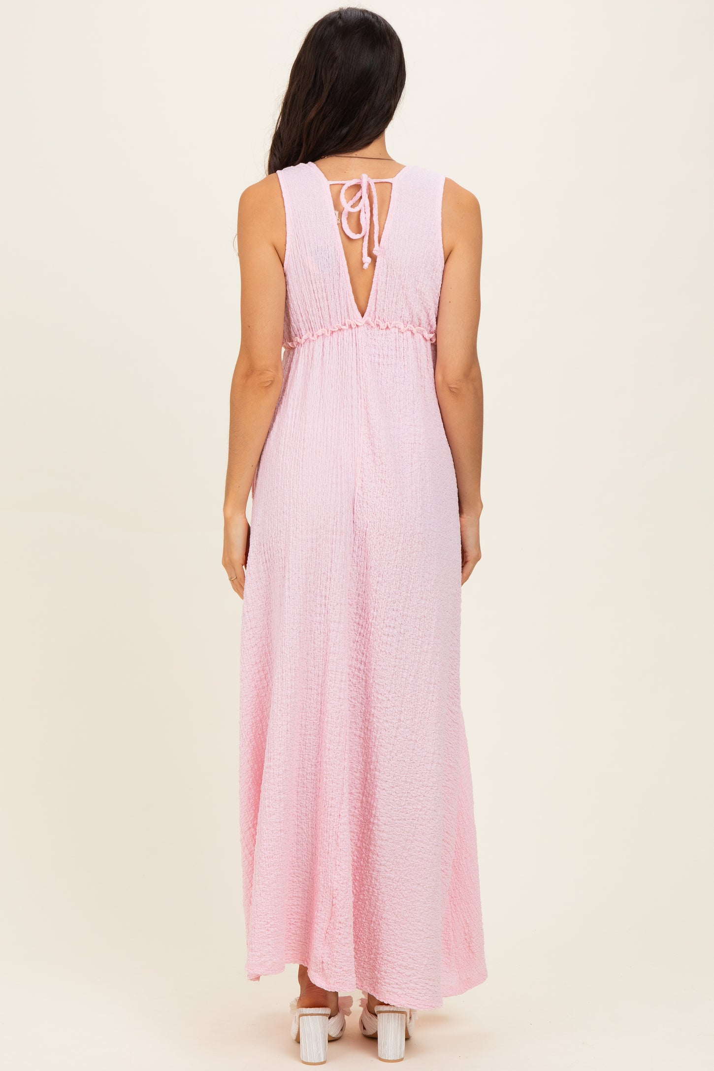 woman wearing a pink sleeveless maxi dress with a back tie and a flowy skirt