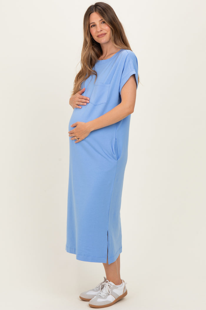 woman wearing a light blue maternity maxi dress with short sleeves and side pockets, showing her baby bump