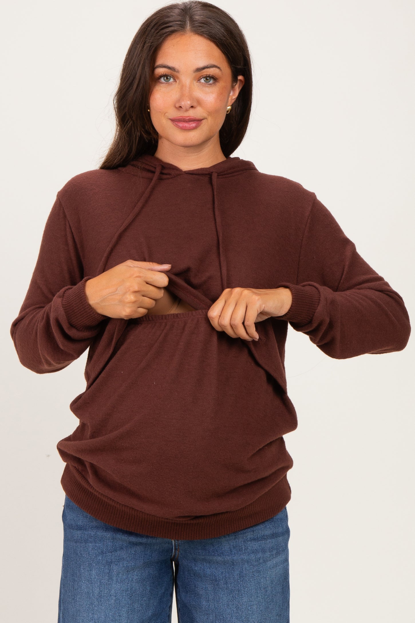 woman wearing a brown maternity hoodie with lifting front for easy nursing access and blue jeans, showing her baby bump
