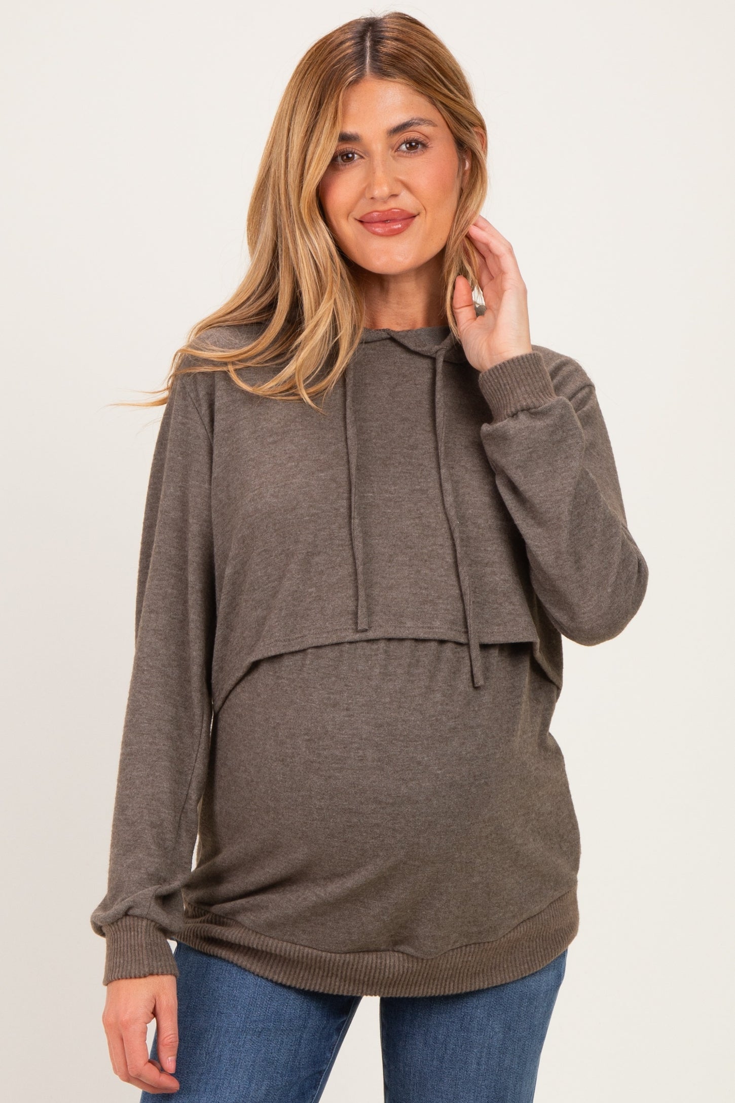 woman wearing a brown cropped maternity hoodie with a hood and long sleeves, showcasing her baby bump