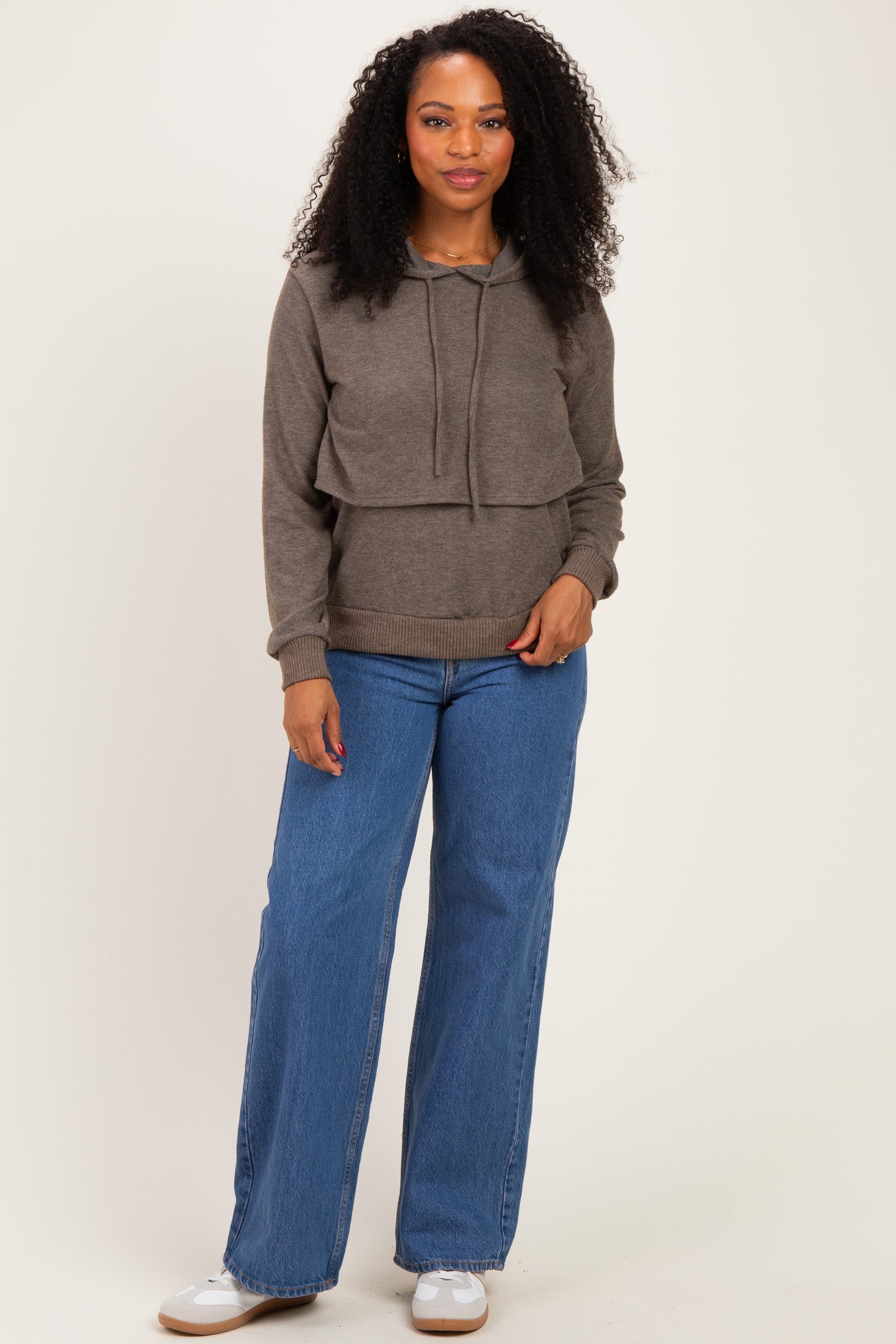 woman wearing a brown cropped hoodie with a drawstring and paired with wide-leg blue jeans