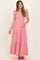 woman wearing a red and white gingham maternity maxi dress with ruffled straps and tiered detailing, holding her baby bump
