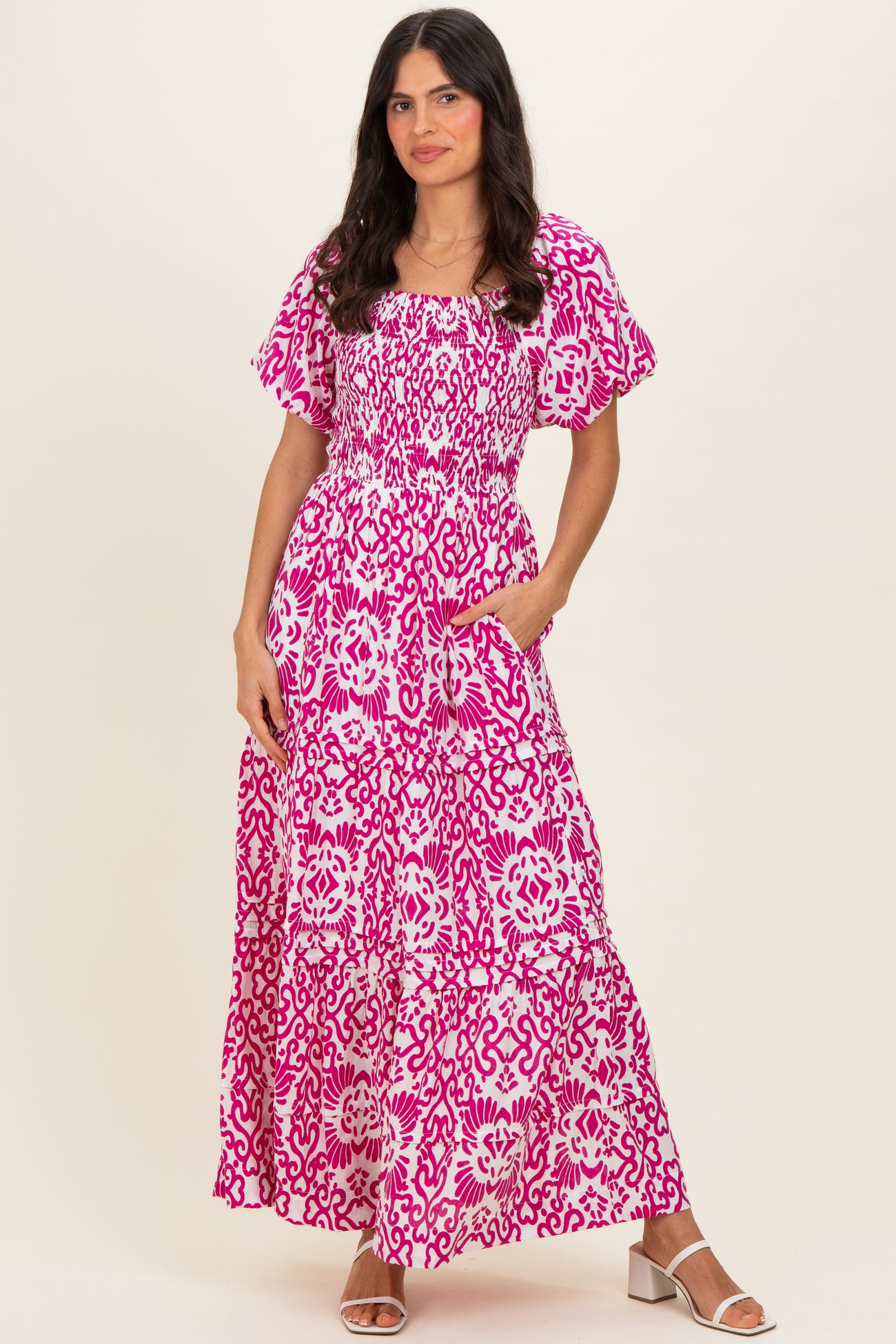 woman wearing a pink floral maxi dress with short flutter sleeves and pockets
