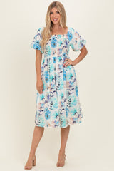 woman wearing a floral print midi dress with puff sleeves in blue and white