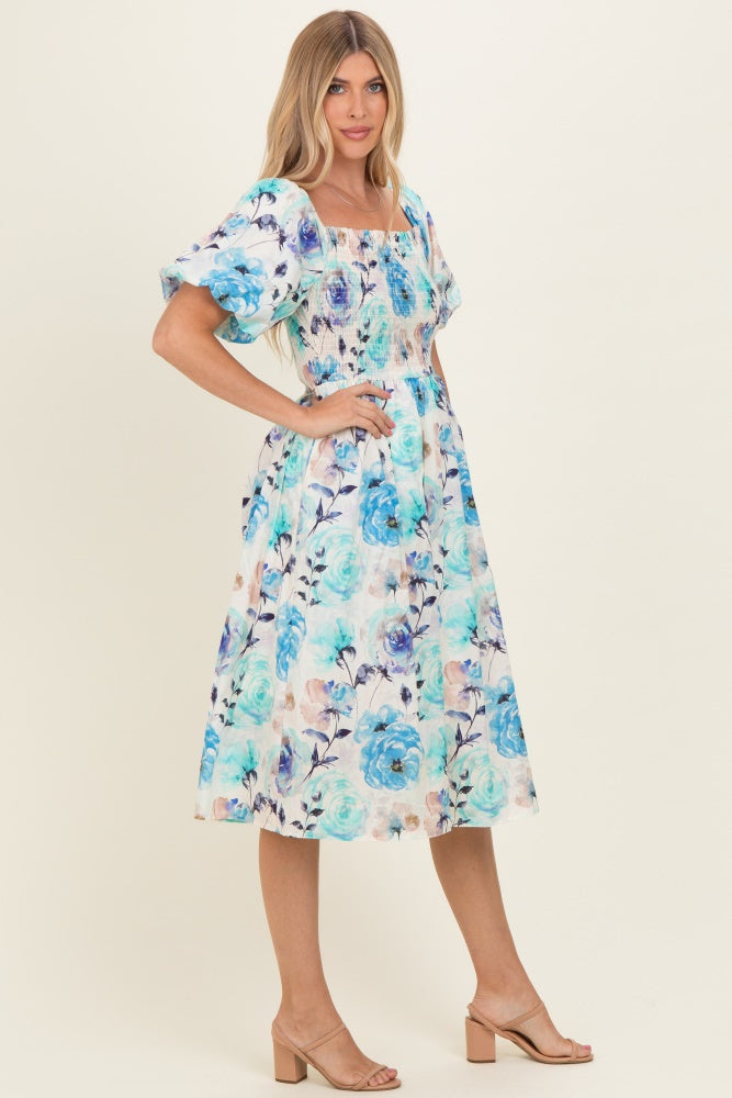 woman wearing a floral print midi dress with blue roses and puff sleeves, styled with heeled sandals