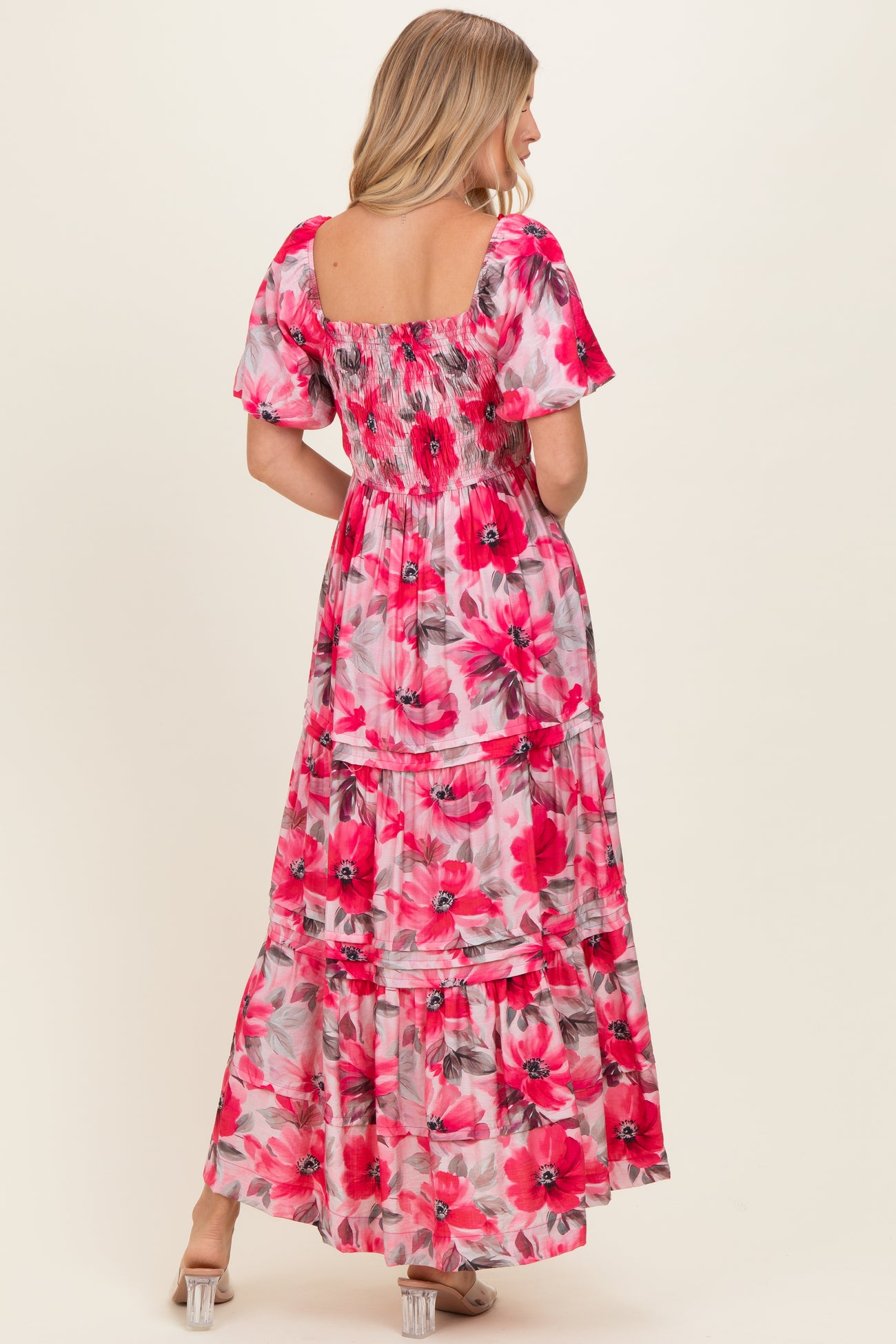 woman wearing a pink floral maxi dress with short puff sleeves and tiered skirt, shown from the back