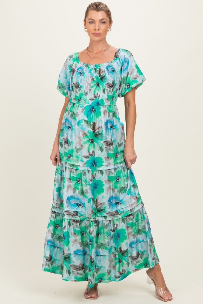 woman wearing a green floral print maxi maternity dress with short sleeves and a tiered skirt, showcasing her baby bump