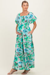 woman wearing a floral patterned maternity maxi dress with puff sleeves and pockets, gently holding her baby bump