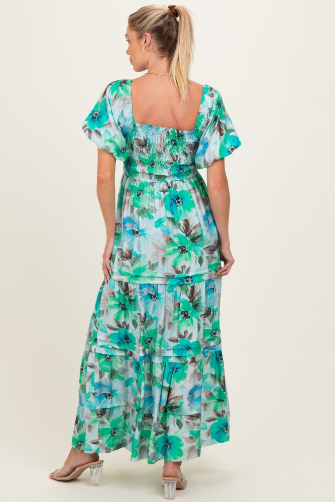woman wearing a floral print maternity maxi dress with puff sleeves and a tiered design, showing a baby bump