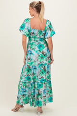 woman wearing a floral print maternity maxi dress with puff sleeves and a tiered design, showing a baby bump