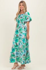 woman wearing a floral print maxi dress in teal and green with puff sleeves and a tiered skirt