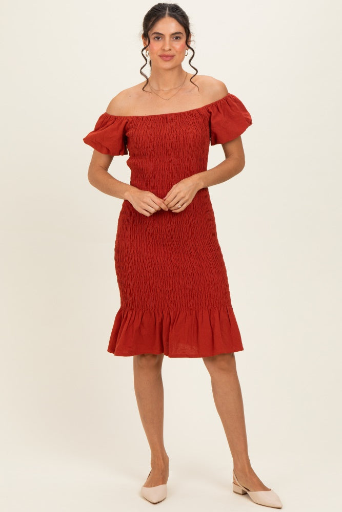 woman wearing a rust off-the-shoulder smocked dress with ruffle hem and short sleeves
