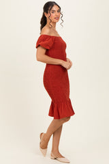 woman wearing a rust off-shoulder smocked dress with short puff sleeves and a flared hem